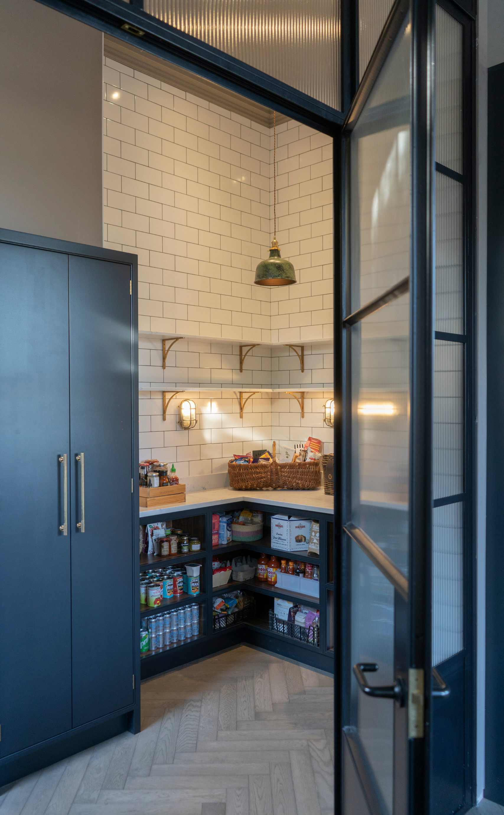 Kitchen Pantry, open shelved, blue cabinetry with white worktop, seen through crittall doors